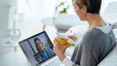 Person sitting on a couch with a laptop on a telehealth video call
