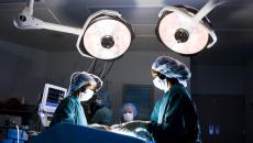 Healthcare providers performing surgery on a patient with lights shining down from the ceiling