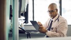 Healthcare provider sitting at a desk while looking at a tablet