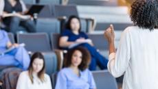 Students in scrubs sitting in a classroom looking at a teacher