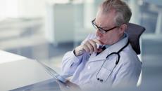 Physician sitting in a chair looking at a tablet