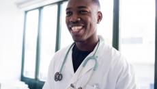 Healthcare provider smiling while wearing a lab coat and stethoscope 