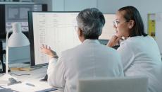 Healthcare workers looking at a spreadsheet on a computer monitor